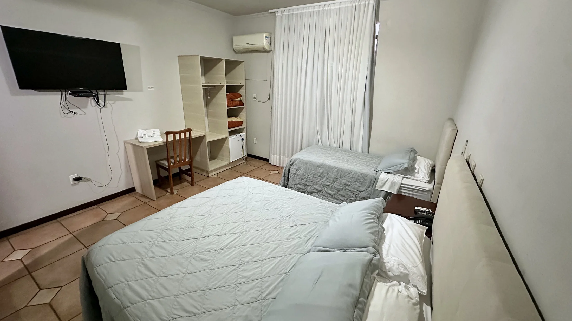 Vista interna de quarto do Hotel Beira Rio com camas, TV e armário